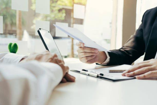 Male manager is talking or explaining about having to dismiss the employee while being handed out a resignation envelope to the employee.